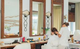 Elegant hair salon interior featuring mirrors, wooden decor, and a hairstylist attending to a client.