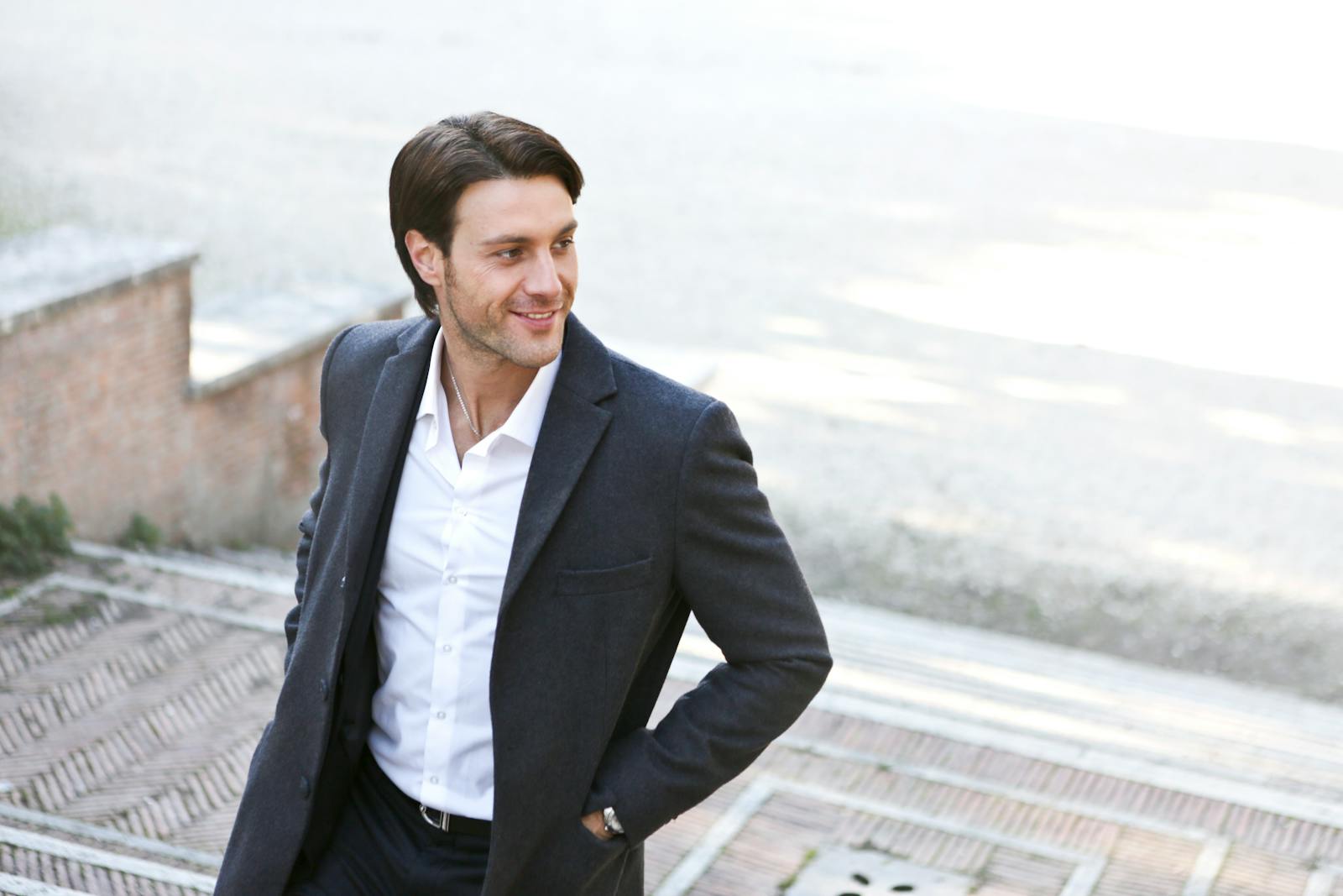 Confident man in a suit smiling while walking outdoors, showcasing fashion and style.