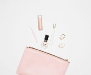 white nail polish bottle and pink leather zip pouch