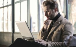 man holding his chin facing laptop computer